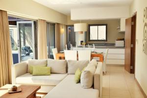 a living room with a white couch and a kitchen at Athena Villas by Fine & Country in Grand-Baie