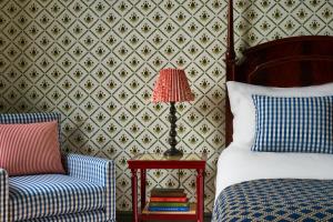 a bedroom with a bed and a chair and a lamp at The Mitre, Hampton Court in Kingston upon Thames