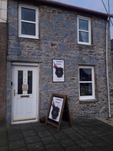 a brick building with a white door and a sign in front at Readers Retreat in Wigtown