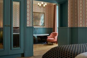 1 dormitorio con paredes verdes y silla rosa en The Mitre, Hampton Court en Kingston upon Thames