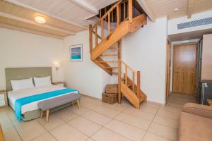 a bedroom with a bed and a wooden staircase at Grand TheoNi Boutique Hotel & Spa in Vasiliki