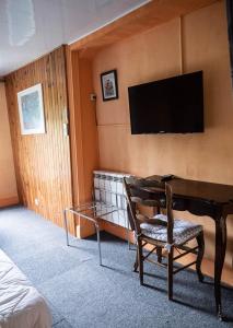 Pokój z biurkiem i telewizorem na ścianie w obiekcie Hotel Beau Rivage w mieście Pont-en-Royans