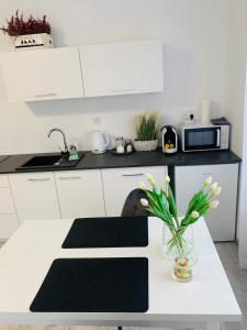 a white kitchen with a table with a vase of flowers at Apartament Walczaka 22 MIEJSCE PARKINGOWE in Gorzów Wielkopolski