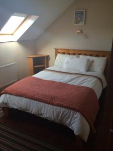 een slaapkamer met een groot bed en een rode deken bij Ard Mhuiris B&B in Inis Mor