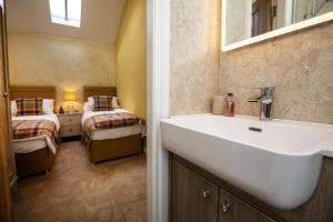 a bathroom with a sink and a bedroom with two beds at Thirley Cotes Farm Cottages in Scarborough