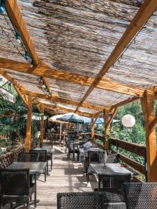 eine Terrasse mit Tischen und Stühlen unter einem Holzdach in der Unterkunft Hotel Beau Rivage in Pont-en-Royans