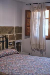 1 dormitorio con cama y ventana con cortina en Casa rural fuentelgato, en Huerta del Marquesado