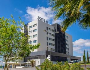 um prédio branco com árvores na frente em Santarem Hotel em Santarém