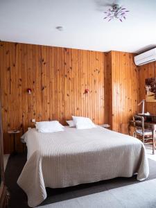 1 dormitorio con 1 cama con pared de madera en Hotel Beau Rivage, en Pont-en-Royans