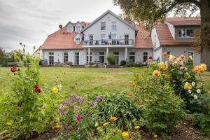 duży biały dom z kwiatami na dziedzińcu w obiekcie Herrenhaus Jürgenshof w mieście Alt Schwerin