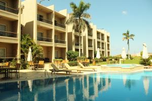 a hotel with a swimming pool and a resort at Panacea Suites Hotel in Borg El Arab