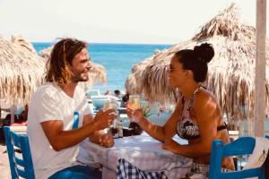 a man and a woman sitting at a table on the beach at Dodo's Perivolos in Perivolos