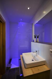 baño con lavabo blanco e iluminación púrpura en Chalet Gonda inklusive Premiumcard, en Galtür