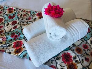 twee handdoeken met een bloem op een bed bij Pousada Ello in São Miguel do Gostoso