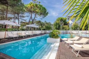 une piscine avec des chaises et des parasols dans un hôtel dans l'établissement Hotel Rex, à Lignano Sabbiadoro