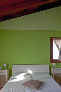 Dormitorio verde con cama y ventana en La Corte D'Emilio B&B, en Vignola