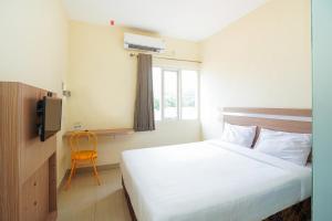 a bedroom with a bed and a window and a chair at Pratisarawirya Guesthouse by ecommerceloka in Surabaya