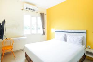 - une chambre avec un grand lit blanc et une fenêtre dans l'établissement Pratisarawirya Guesthouse by ecommerceloka, à Surabaya