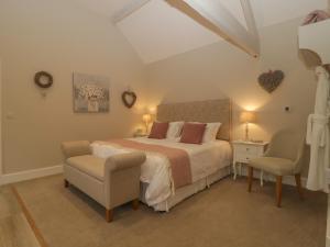 a bedroom with a large bed and a chair at Barn Owl Cottage in Salisbury