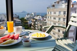 einen Tisch mit einem Frühstück mit Eiern und Obst auf dem Balkon in der Unterkunft Ritz Leblon in Rio de Janeiro