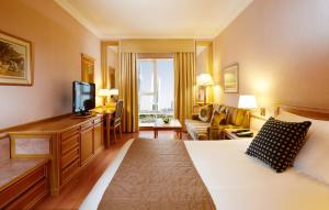 ドバイにあるMillennium Plaza Downtown Suitesのベッドとテレビが備わるホテルルームです。