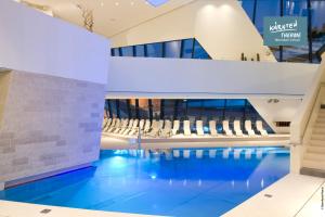 a pool in the lobby of a building with chairs at Appartementhaus Karawankenhof in Villach