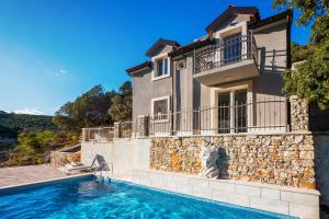 a villa with a swimming pool in front of a house at Holiday home Beyla in Pučišća