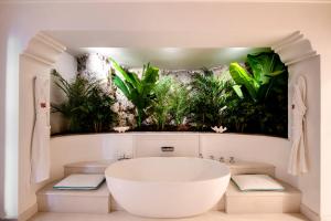 a bathroom with a bath tub and plants on the wall at Il San Pietro di Positano in Positano
