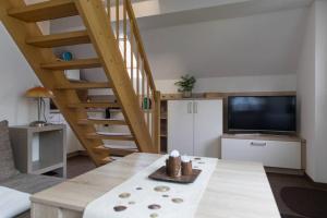 ein Wohnzimmer mit einem Tisch, einem TV und einer Treppe in der Unterkunft Weide - gemütliches Ferienhaus am Anger in Kloster, Insel Hiddensee in Kloster