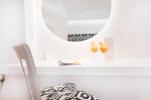 a white room with a mirror and two glasses on a shelf at Stelia Mare Boutique Hotel in Naousa