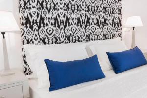 a bed with two blue pillows and a black and white curtain at Stelia Mare Boutique Hotel in Naousa