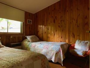 1 Schlafzimmer mit 2 Betten, einem Stuhl und einem Fenster in der Unterkunft Cabaña Las Patagüas - Coñaripe in Coñaripe