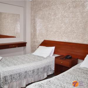 1 dormitorio con 2 camas, mesita de noche y espejo en Hotel 7 Calles, en Santa Cruz de la Sierra