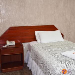 un letto con testiera in legno e un telefono su un tavolo di Hotel 7 Calles a Santa Cruz de la Sierra