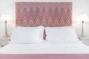 a white bed with two pillows and a chevron headboard at Stelia Mare Boutique Hotel in Naousa