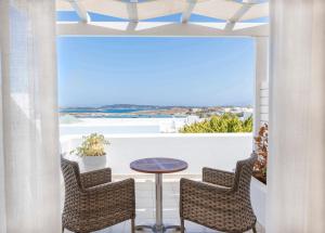 a balcony with a table and chairs and a view of the ocean at Stelia Mare Boutique Hotel in Naousa