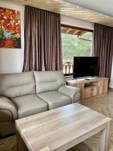 - un salon avec un canapé et une télévision dans l'établissement Къщи за гости "Комплекс ОАЗИС", à Dospat