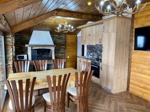 a kitchen with a wooden table and chairs at Къщи за гости "Комплекс ОАЗИС" in Dospat