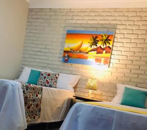 two beds in a room with a painting on the wall at Pousada Ello in São Miguel do Gostoso