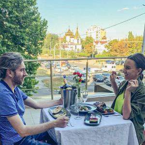 Ein Mann und eine Frau sitzen an einem Tisch mit Essen in der Unterkunft Manhattan Hotel & Restaurant in Chişinău