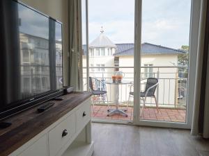 ein Wohnzimmer mit einem Flachbild-TV und einem Balkon in der Unterkunft Residenz "bel-vital" Binz - WG28 mit kleinem Meerblick und Balkon in Binz