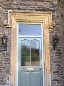 uma porta azul num edifício de pedra com duas luzes em The Lake Lodge, Wansfell Holme, Windermere em Ambleside