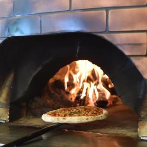 Une pizza est préparée dans un four en briques. dans l'établissement Hotel Novarello Resort & Spa, à Granozzo con Monticello