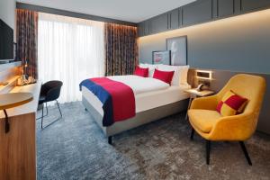 a hotel room with a bed and a chair at Holiday Inn - Hamburg - HafenCity, an IHG Hotel in Hamburg