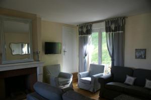 ein Wohnzimmer mit einem Sofa, Stühlen und einem Kamin in der Unterkunft Entre Phare et Moulin in Verzenay