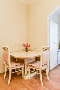een eettafel met 2 stoelen en een vaas met bloemen bij Nevsky Row Hotel - Nevsky 100 in Sint-Petersburg