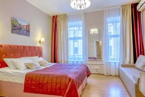 a bedroom with a bed and a couch and windows at Nevsky Row Hotel - Nevsky 100 in Saint Petersburg