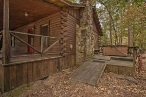 uma cabana de madeira com um alpendre e um deque em Timber Brooke Cabin Hot Tub and Central Location! em Broken Bow