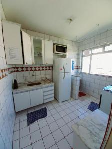 a kitchen with white cabinets and a refrigerator at Praia do morro com Wi-Fi in Guarapari