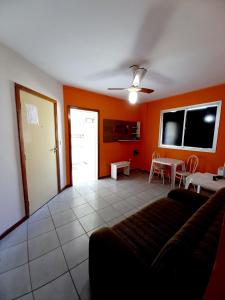 een woonkamer met oranje muren en een bank en een tafel bij Praia do morro com Wi-Fi in Guarapari